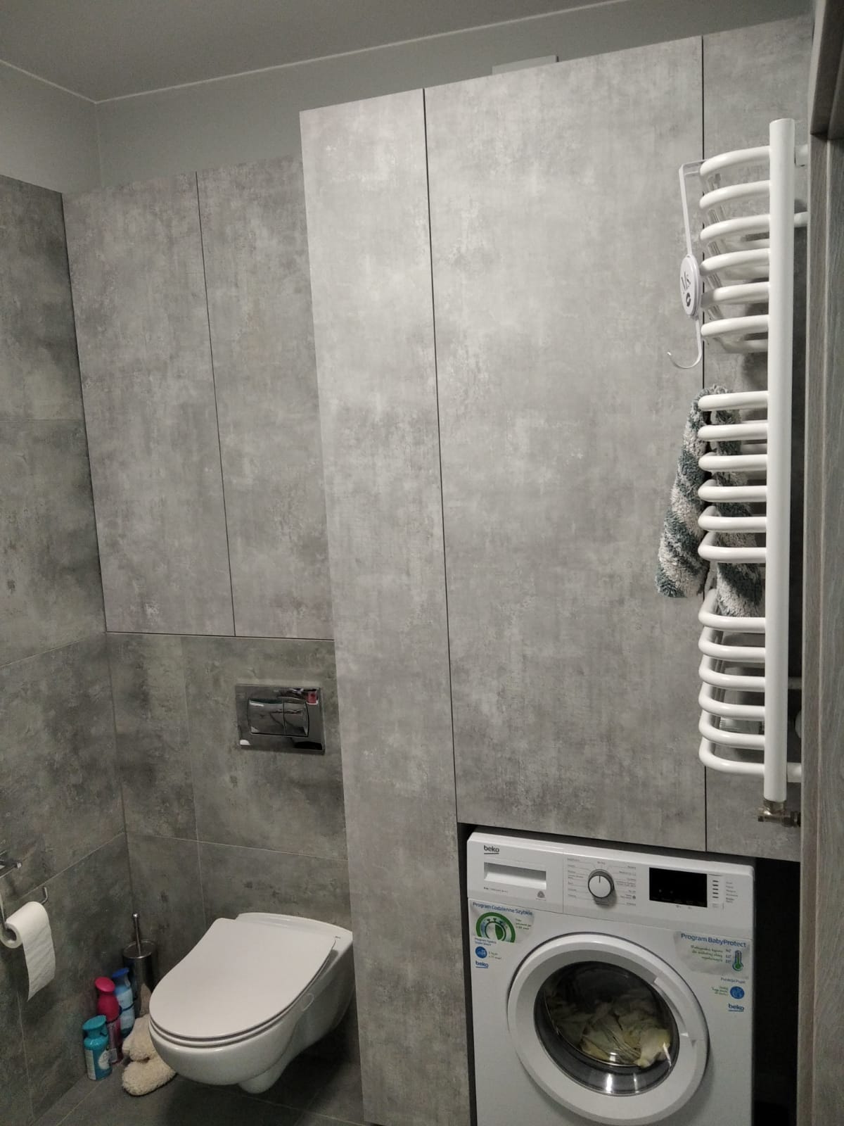 Szara zabudowa łazienkowa z pralką i WC.