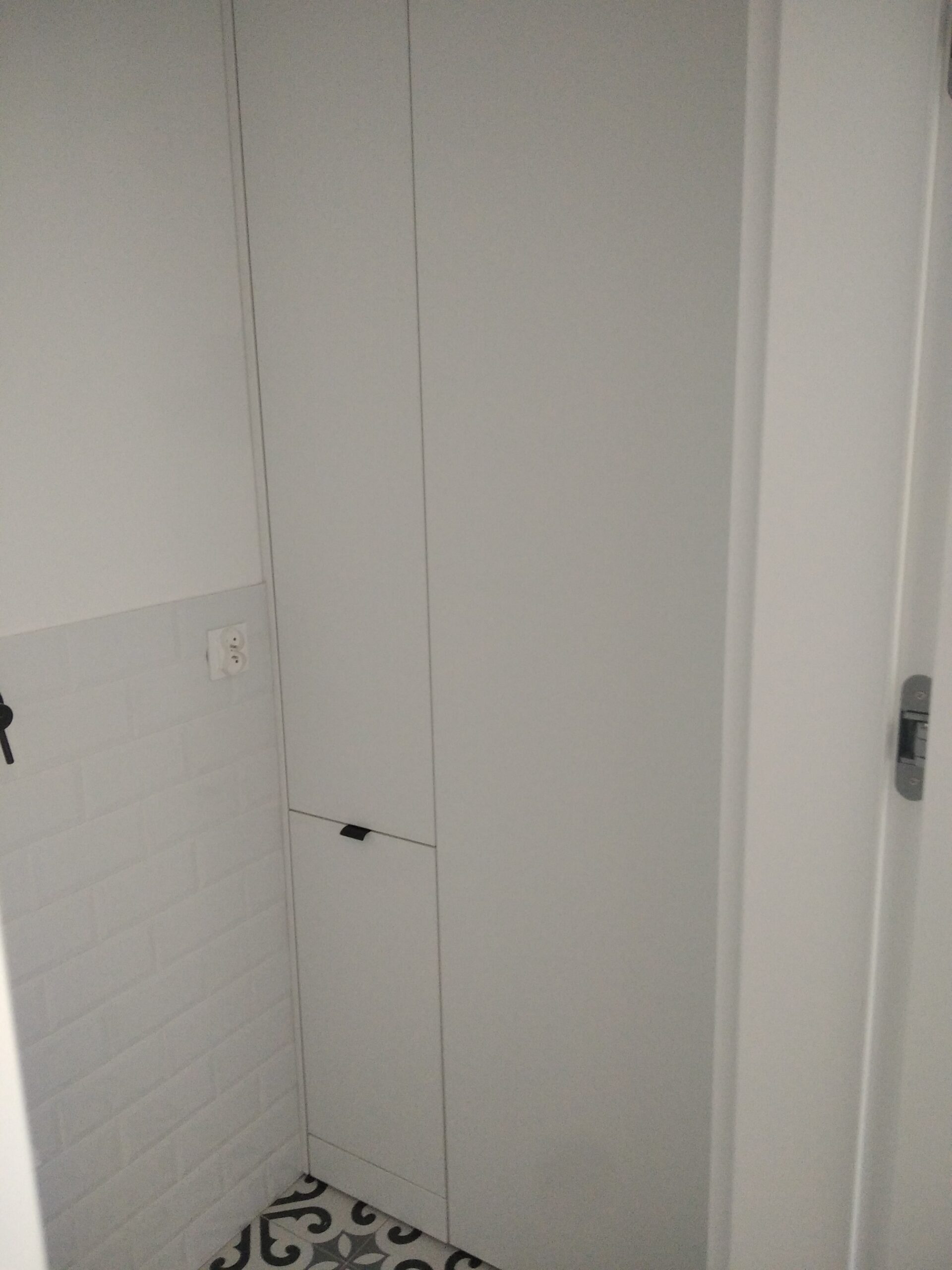 Biała zabudowa wnęki z szafkami i szufladą.